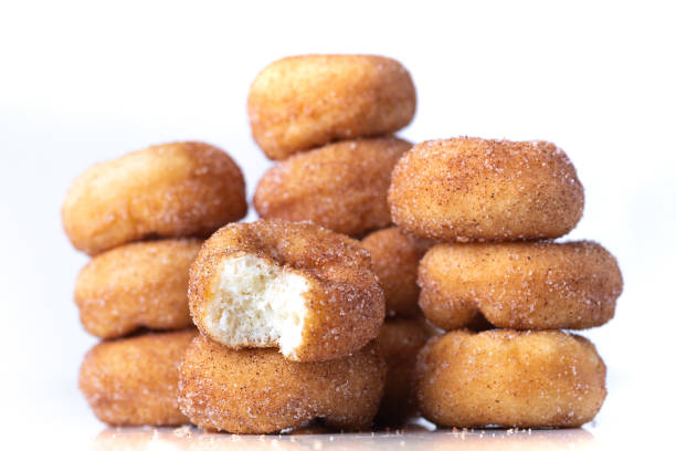 A stack of warm cinnamon sugar mini donuts, one with a bite taken out